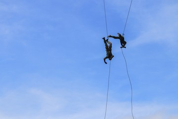 Soldier two rappelling with rope on blue sky