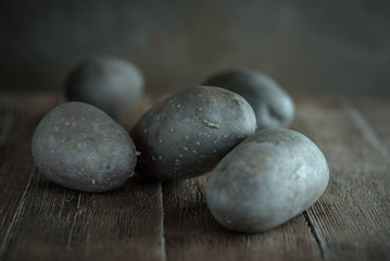 Raw potatoes on wooden table in rustic style on a brown background