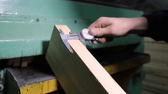 Carpenter with calipers measuring wood in workshop