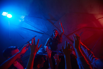 Cheerful girl entertaining ecstatic crowd of dancers