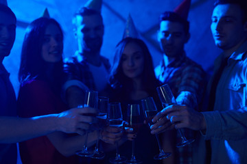 Group of friends clinking flutes with champagne at booze