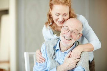  Portrait of elderly gray haired man embracing his wife and smiling enjoying quiet retirement days...