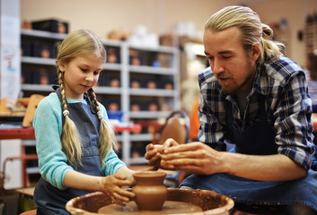 Creative man explaining his daughter how to make jugs