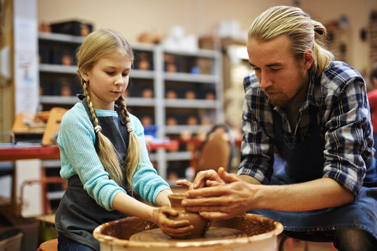 Family of father and daughter making jugs in workshop together