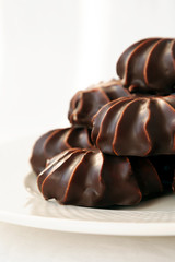Pile of marshmallows glazed with chocolate. Many coated elegant zephyr dessert isolated on white. Sweet elegant dessert on a plate