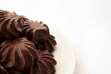 Pile of marshmallows glazed with chocolate. Many coated elegant zephyr dessert isolated on white. Sweet elegant dessert on a plate