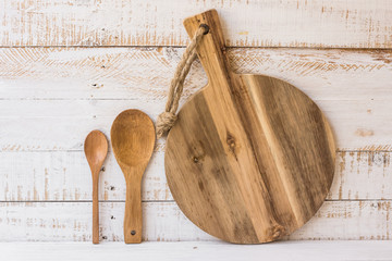 Round wooden cutting board and spoons standing on white kitchen table, minimalistic style, abstract, kitchen interior