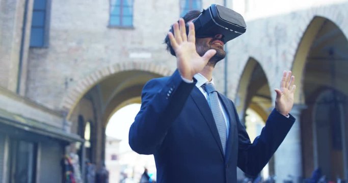 A businessman in a suit uses augmented reality in the city among the people. Concept: immersive technology, augmented reality and futuristic business.