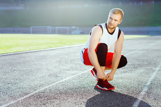 Sportsman crouched in red sneakers