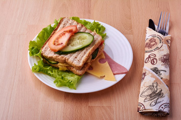 Sandwich on plate and cutlery.