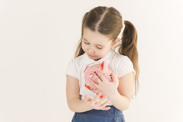 Close up portrait of happy young little girl snuggling pink piggy bank. Education, school and money saving concept. Junior Savings Account concept
