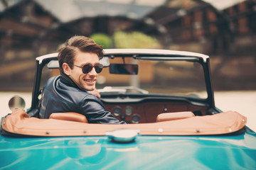 Fashion man sitting in luxury retro cabriolet car outdoors
