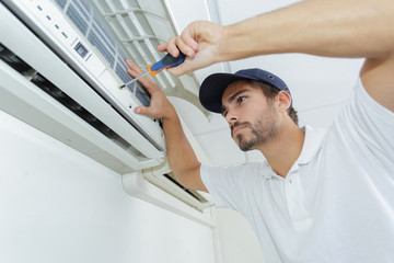 portrait of mid-adult male technician repairing air conditioner