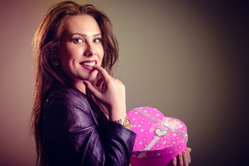 Amazed sexy attractive woman wearing black leather jacket holding red heart box present gift in...