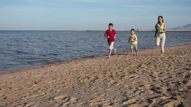 Group of three kids running at the beach in Egypt resort, slow m