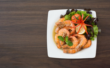 Shrimp boiled with honey and salt in white dish on dark table thai food