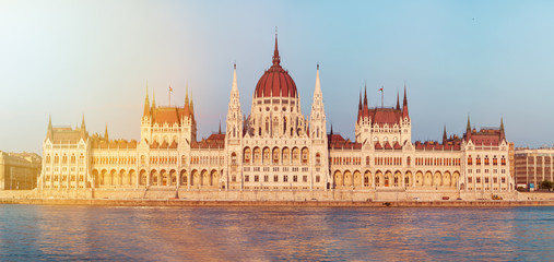 Naklejka premium Parliament building in Budapest, Hungary. Building facade with reflection in water. Beautiful sunset light