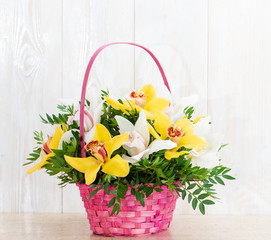 Fototapeta na wymiar Basket with orchids on a wooden background