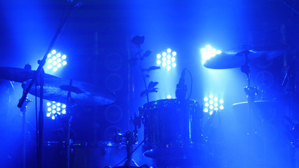 The scene with the drum kit and beautiful searchlights in blue colors