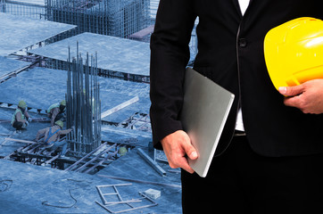double exposure of businessman hold in hand yellow safety helmet and laptop computer notebook industrial concept on construction site workers background, color tone effect.