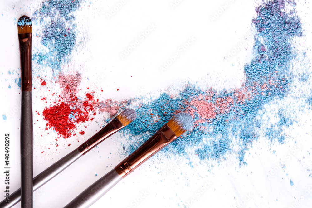 Wall mural makeup brushes with blush or eyeshadow of pink, blue and coral tones sprinkled on white background