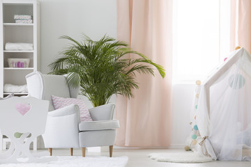Baby room with armchair, crib and plant