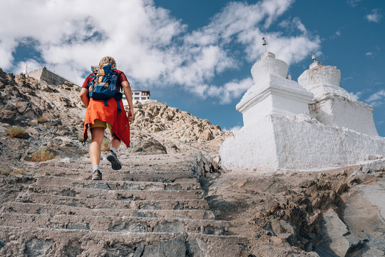Tourist man climbs up stairs to tibetan holy place in Himalaya mountain