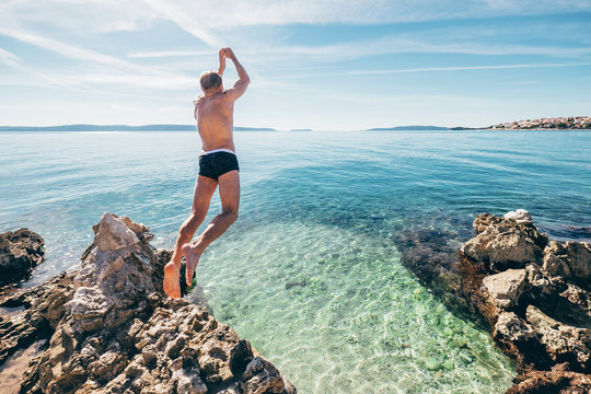 Man jumps in clear crystal water on Adriatic Sea Bay