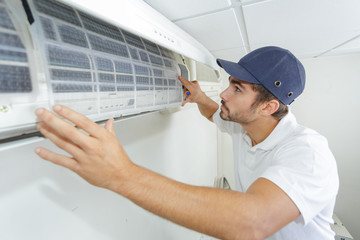 portrait of mid-adult male technician repairing air conditioner