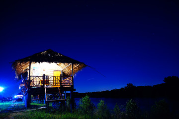 Straw house near small lake with sky in nightime, countryside of Thailand