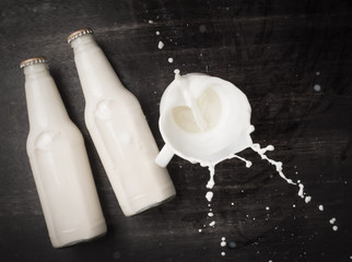 Milk splash and bottle milk on dark wooden table,Top view