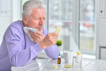 Sick elderly man taking medicine