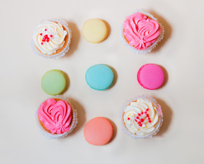 Fototapeta na wymiar Sweet colorful macaroons and cupcakes on beige background