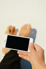 Business man hand holding using mobile smart phone on light background. Closeup view of mock up display network connection