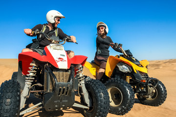 Fototapeta na wymiar Quad driving people - happy smiling couple bikers in sand desert.