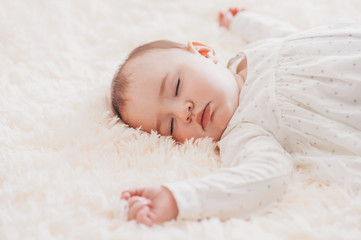 Close-up portrait cute baby lying on a fur blanket while sleeping