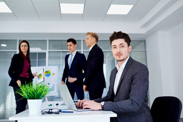 Young guy with a laptop at  table in  modern office.