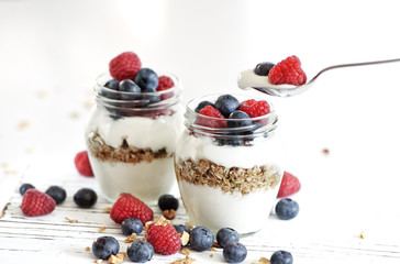 Yogurt with bluberry and raspberry in the glass jars with berries around