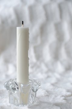 Flameless candle. White candle in candle holder made of glass, against white background.