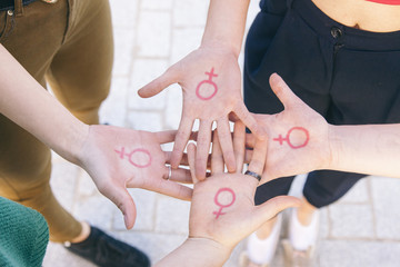 close up of small group of women with the symbol of feminism written on her hands