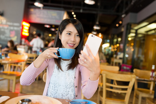Woman taking selfie by mobile phone in cafe