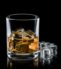 Glass of whisky with ice on a black