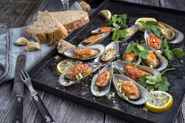 Backed Green Shell Mussels on old rustic Sheet with Bread