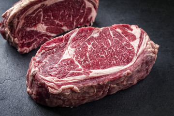 Two raw dry aged Wagyu Rib Eye Steaks on a slate