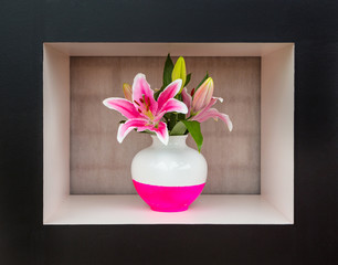 Giant white and pink lily in white and pink vase stands in black and white frame, in the background brick wall under cloth. Bouquet of lilies with vase. Flowers in vase at design.