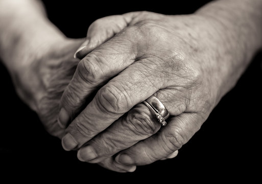 Monochrome close up of an elderly married lady's hands.
