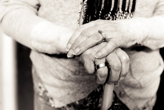 Old woman's hands on umbrella handle. Black and white.
