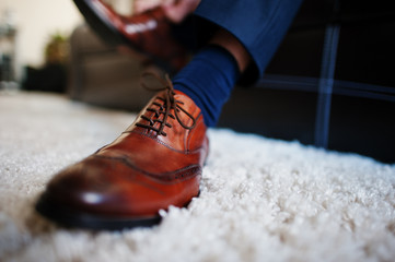 Man's hands tying shoelace of his new brown leather shoes. Groom morning.