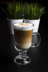 Coffee latte in a glass with green grass on the background