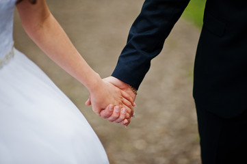 Hand in hand of wedding couple walking outdoor.